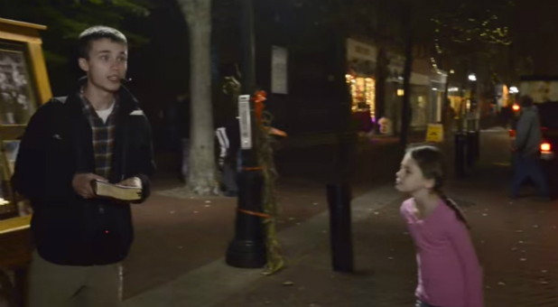 A young girl tries to shout over a street preacher in Salem, Massachusetts.
