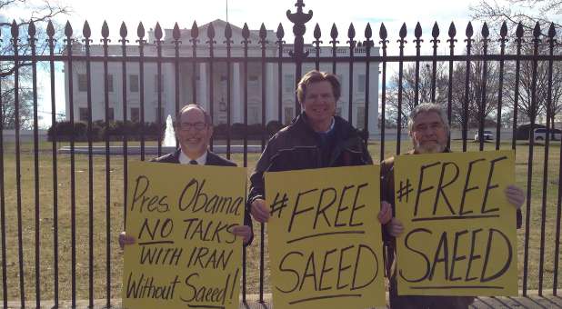 People stand outside the White House with signs asking President Barack Obama to bring home pastor Saeed Abedini.