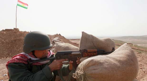 A Kurdish Peshmerga fighter takes up position with weapon at the frontline against the Islamic State.