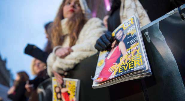 Fans hold magazines featuring