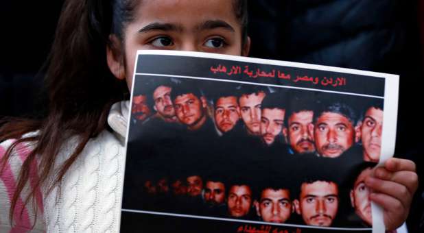 A girl holds up a poster with pictures of the 21 Egyptian Coptic Christians beheaded by Islamic State.