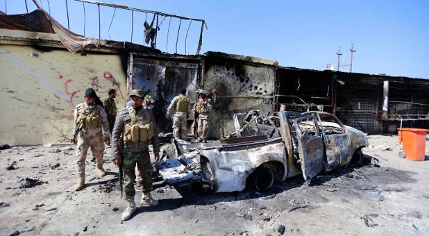 Militias known as Hashid Shaabi inspect a destroyed vehicle of Islamic State militants in the town of al-Alam.