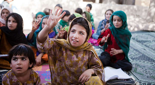 A Muslim girl raises her hand at an inclusive mosque event.