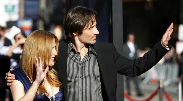Cast members David Duchovny (R) and Gillian Anderson wave at fans at the movie premiere of