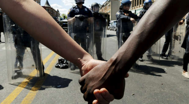 Demonstrators hold hands in front of Baltimore Police.