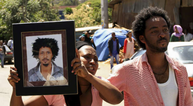 A woman holds a photo of a man said to be one of the 30 Ethiopians martyred by the Islamic State.