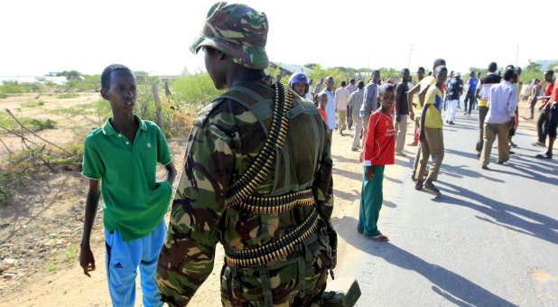 A Kenya Defense Force soldier stops a boy from moving in the direction where attackers are holding up at a campus in Garissa.