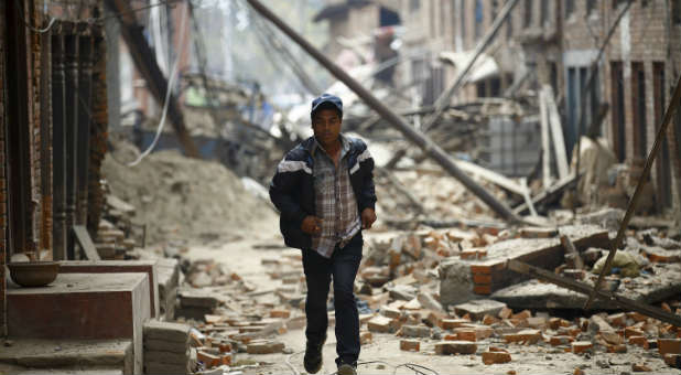 A man runs through the damage caused by the Nepal earthquake and aftershocks.