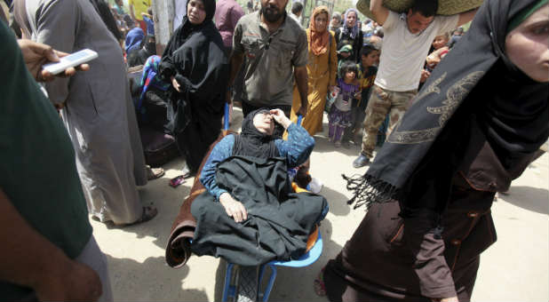 A woman who fainted while fleeing Islamic State militants is carted by a wheelbarrow.