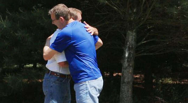 Philip Robinson (standing on the right) and Ron Hammer embrace at Hammer's Virginia home, their first face-to-face meeting since Hammer's sentencing in 1987.
