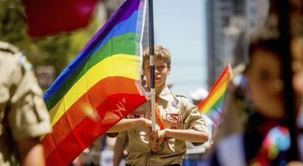 A Boy Scout holds a gay flag.