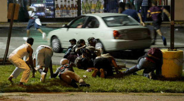 Protesters take cover after shots were fired on the anniversary of Michael Brown's death.