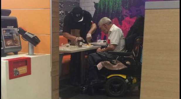 A McDonald's employee stops mid-shift to serve an elderly gentleman.