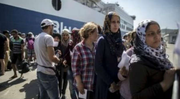 Abeer (R), a 26-year-old Syrian migrant from Deir Al Zour in war-torn Syria, queues with others to buy a ticket to embark a ferry to Athens on the Greek island of Lesbos.