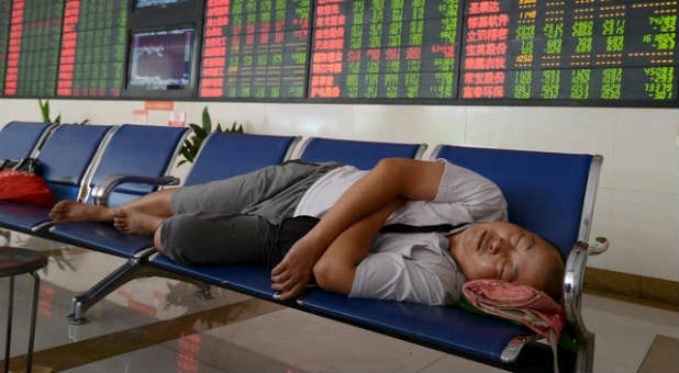 A Chinese investor naps in front of the stock monitors.