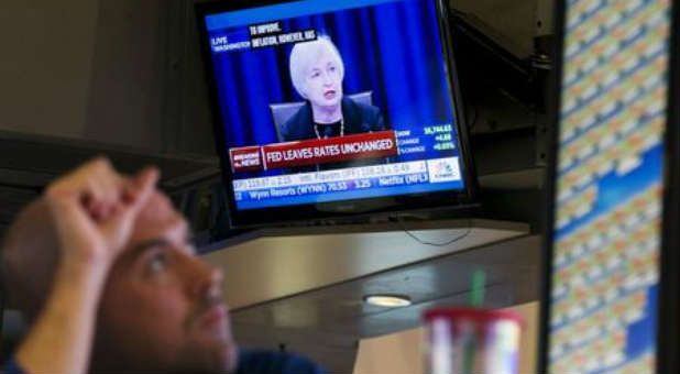 A trader works underneath a television screen showing Federal Reserve Chair Janet Yellen announcing that the Federal Reserve will leave interest rates unchanged on the floor of the New York Stock Exchange in New York.