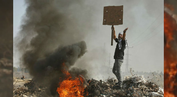 A Palestinian protester shouts during clashes with Israeli troops. In a recent attack, an elderly woman was saved by proclaiming the name of