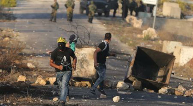 A Palestinian protester flees Israeli troops on the