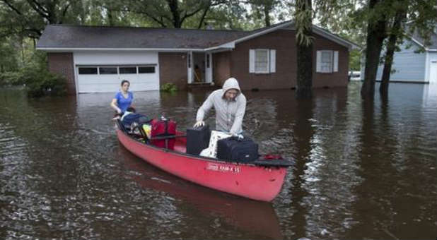 South Carolinians escape their flooded home via canoe.