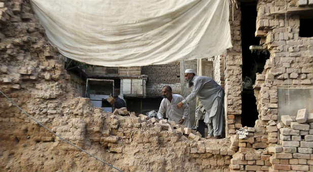 Residents clear the rubble of a house after it was damaged by an earthquake in Peshawar, Pakistan.