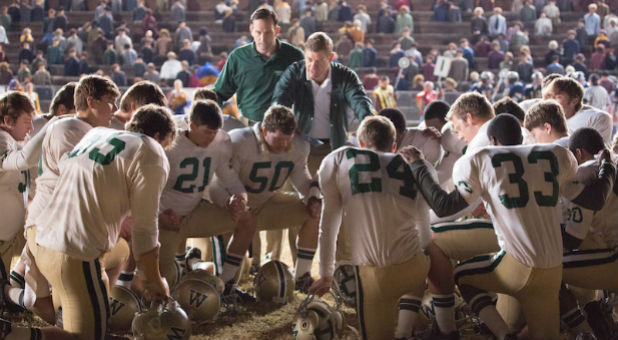 The Woodlawn High School football team, led by defensive coordinator Jerry Stearns (Kevin Sizemore, center left) and head coach Tandy Gerelds (Nic Bishop), pause to pray before an important game in 'Woodlawn.'