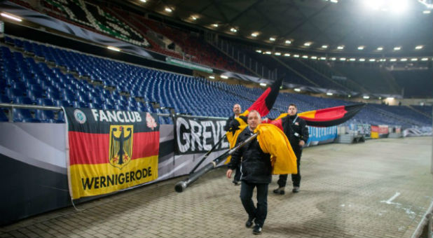 Crewmembers work to clear a German football stadium after bomb threats.