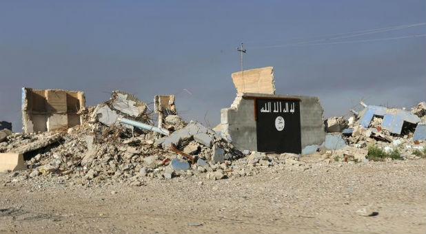 A destroyed building with an homage to the Islamic State painted on one of the remaining walls.