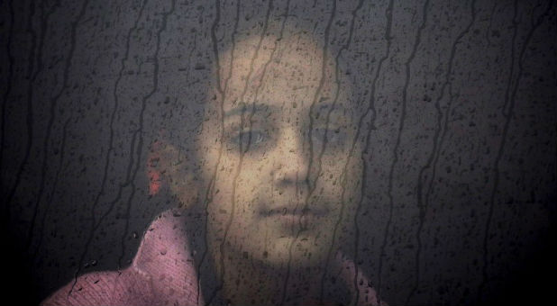 A little refugee girl gazes out the widow.