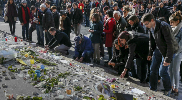 People lay flowers on a memorial for the victims of the Paris attacks.