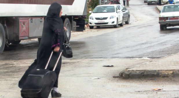 Woman crossing the Lebanese border back into Syria, March 2014. High medical fees force many refugees to return to Syria for treatment