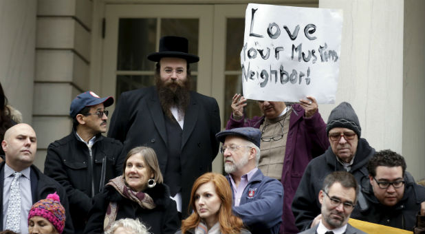 People opposed to Republican presidential Donald Trump's proposal to ban Muslims from entering the United States stand on the steps of New York's City Hall during an interfaith rally in Manhattan.