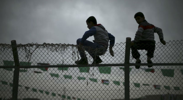 Palestinian boys sit on a fence.