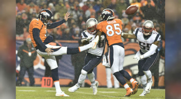 Denver Broncos punter Britton Colquitt (4) punts while Virgil Green blocks against the New England Patriots. Both players have faith in Jesus Christ.