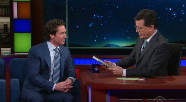 Stephen Colbert, right, holds a copy of Joel Osteen's latest book,