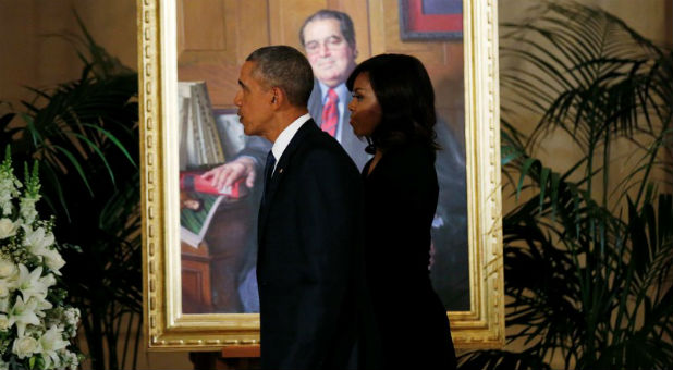 The Obamas walk by a painting of Antonin Scalia.