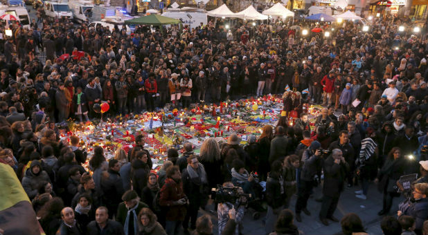 People gather at a street memorial for the victims of the Brussels attacks.