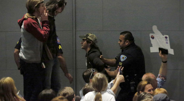 Security guards escort protesters out of a Donald Trump rally.