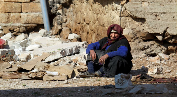 A Syrian woman sits amid the rubble.