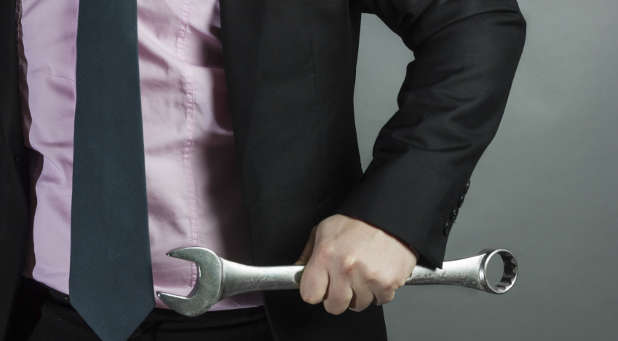 Businessman carrying wrench