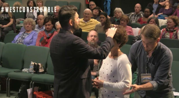 Charlie Shamp prays over a woman March 3 at the Seattle Revival Center. The man in back of her is known as a