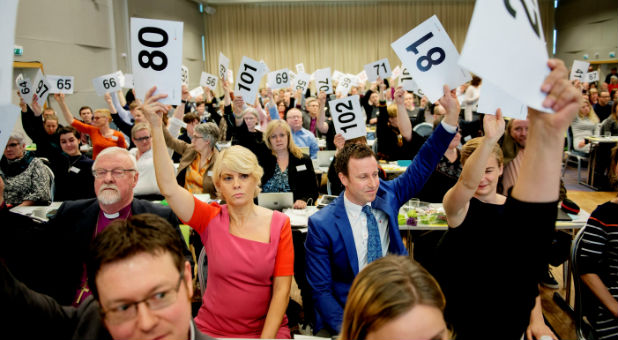 Norwegian Church Council leader Kristin Gunleiksrud Raaum (in red) and Chairman of the Oslo diocesan council Gard Sandaker-Nielsen (R) vote on a proposal to allow same-sex marriage within the Norwegian Church.