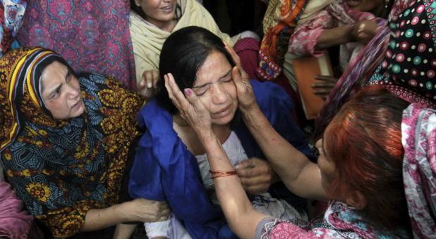 Family members comfort a woman mourns the death of a relative, who was killed in a blast outside a public park on Sunday.