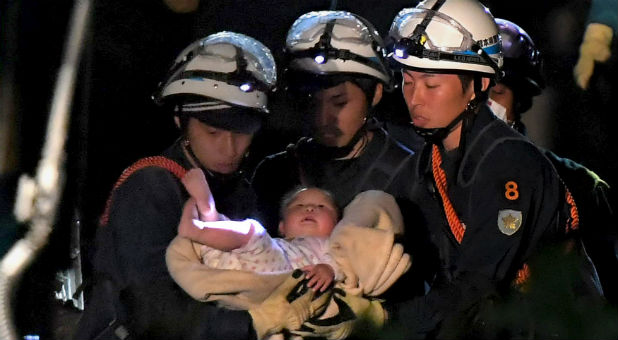 An eight-month-old baby is carried away by rescue workers after being rescued from her collapsed home following an earthquake in Mashiki town, Kumamoto prefecture, southern Japan
