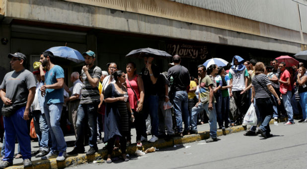 People queue to try to buy basic food items outside a supermarket in Caracas, Venezuela, last month.
