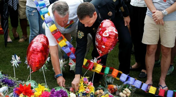Orlando mayor Buddy Dyer and Chief of Police John Mina lay flowers at a memorial service the day after a mass shooting at the Pulse gay nightclub in Orlando