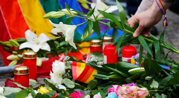 A man places flowers for the victims of the shooting at a gay nightclub in Orlando