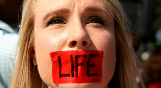 A pro-life protester with tape over her mouth demonstrates outside the U.S. Supreme Court before the court handed a victory to abortion rights advocates, striking down a Texas law imposing strict regulations on abortion doctors and facilities in Washington.