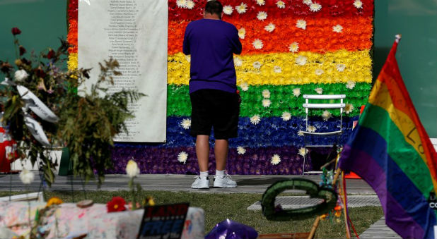 A man pays respect at a rainbow flower wall as part of the makeshift memorial for the Pulse nightclub mass shooting victims last week in Orlando