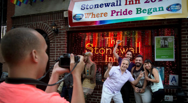 People pose for photos in front of the Stonewall Inn before the start of Pride Week activities.