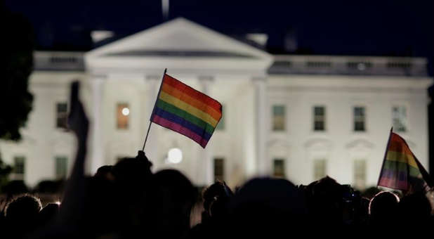 A rainbow flag is held up during a vigil.